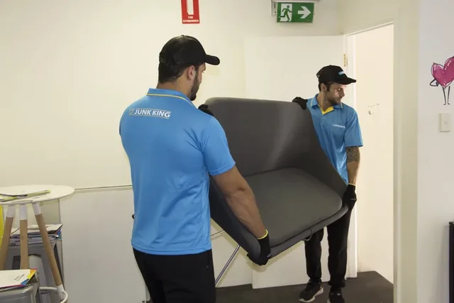 Junk King team carrying a sofa through a doorway